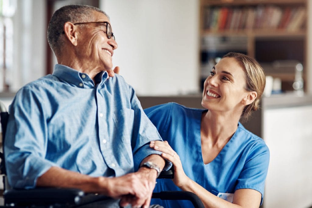 A smiling man and a home health aide talk
