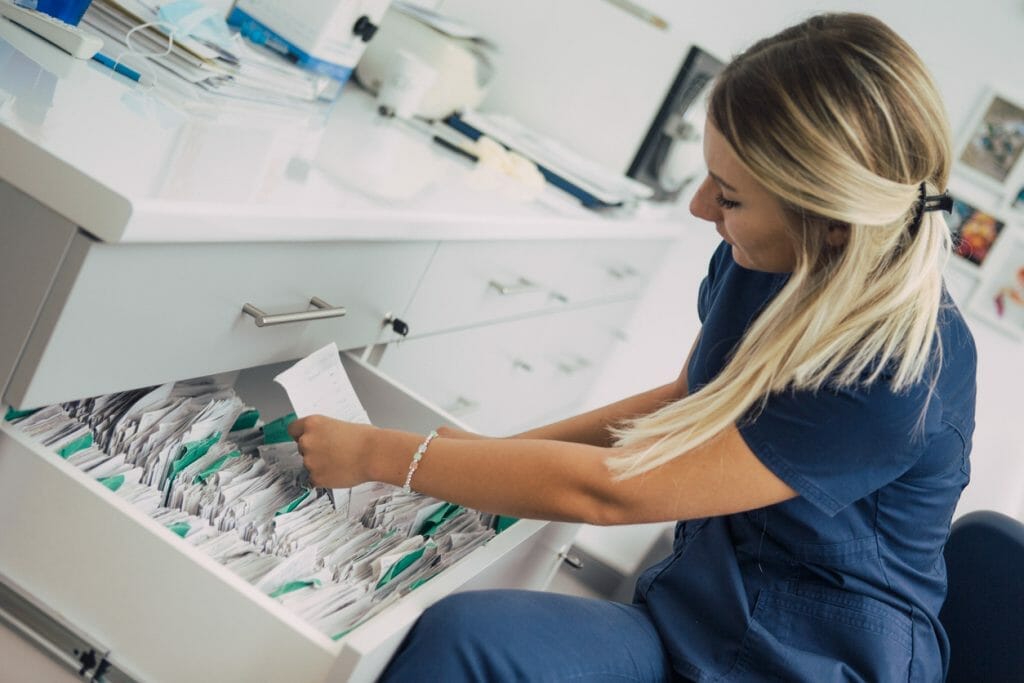 Cost of paper: A healthcare worker goes through a file cabinet