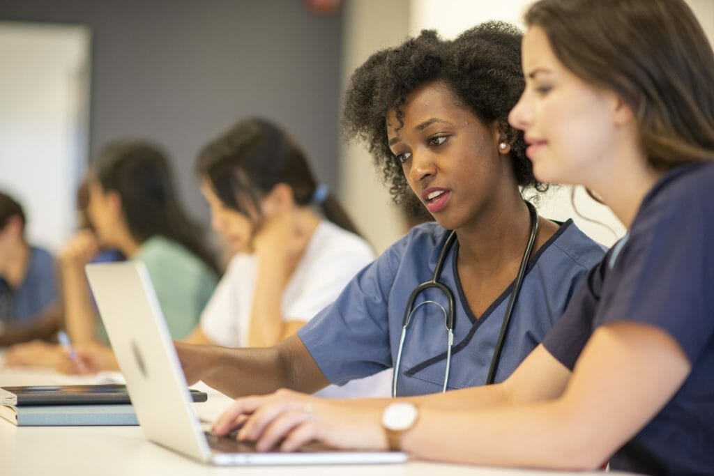 Nurse retention strategies: Two nurses work on a laptop together