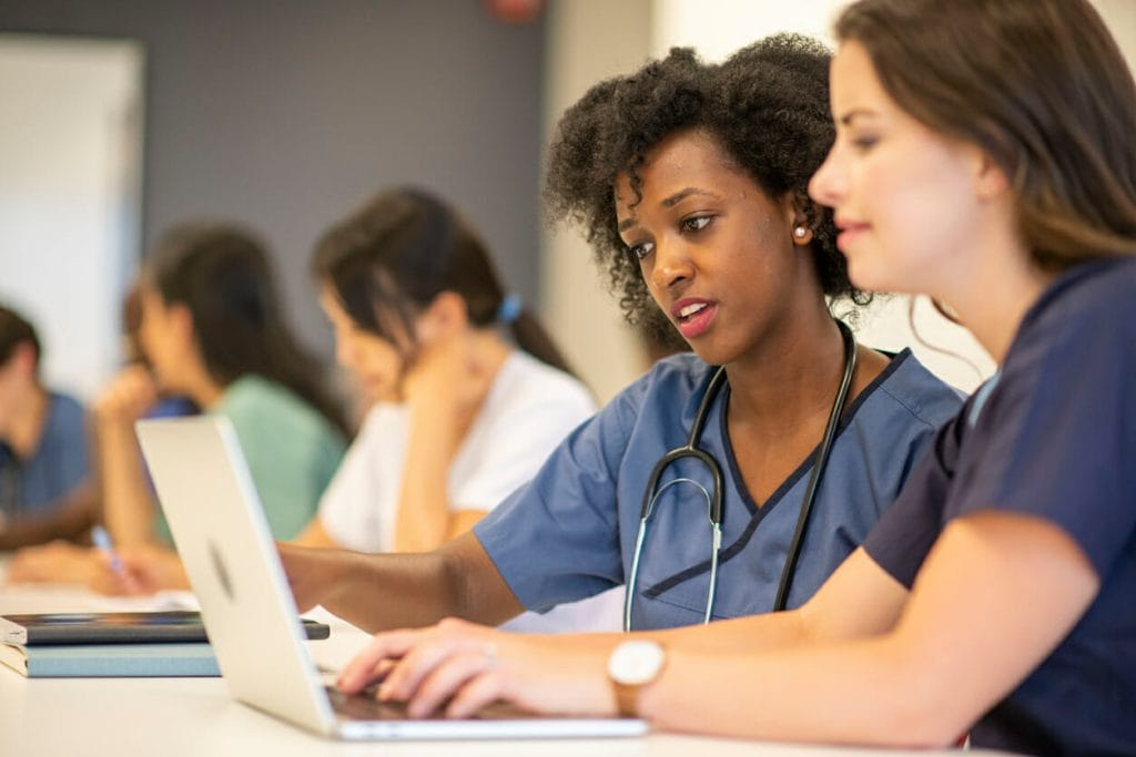 Nurse retention strategies: Two nurses work on a laptop together
