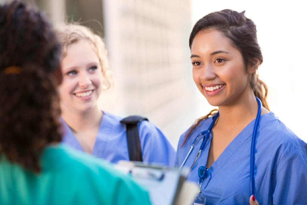 Reducing turnover in healthcare: A group of young nurses talk and smile together