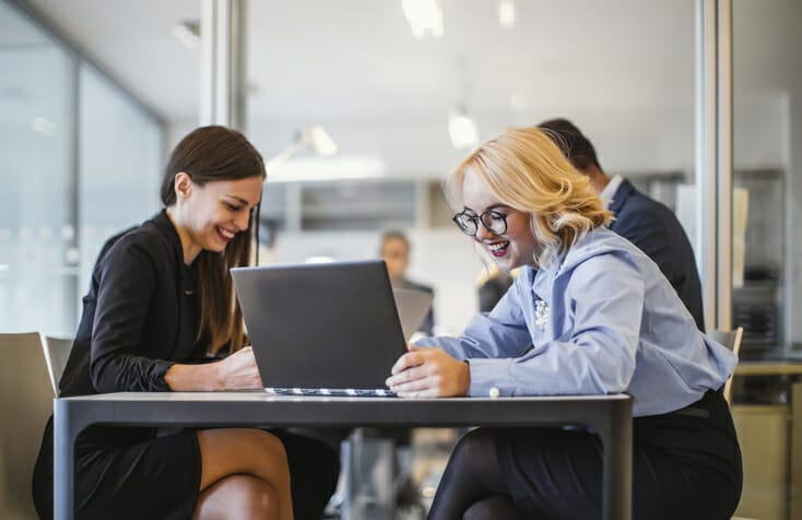 Integrated staffing with Apploi. Two business women work over a computer.