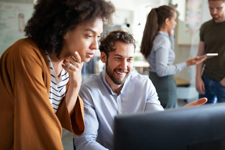 Two workers look at healthcare staffing software on computer
