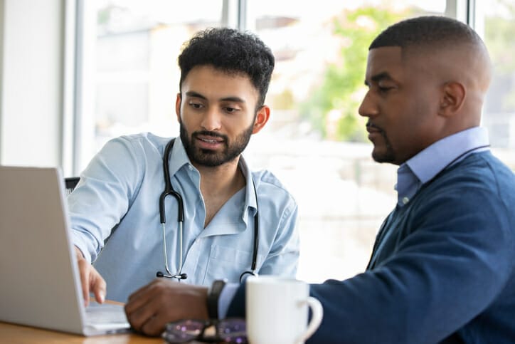 Healthcare accessibility. Two healthcare workers in office attire review something on a laptop.