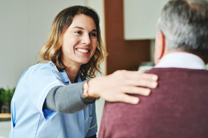 Home healthcare staffing. A healthcare worker smiles at an older man.