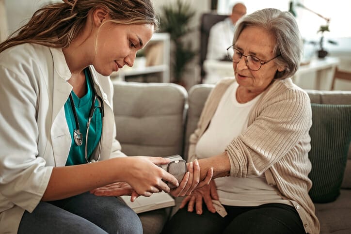 Long term care software. A young healthcare worker works with an older woman.