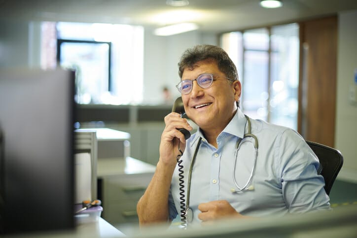 Past candidates. A smiling healthcare worker talks on the phone.