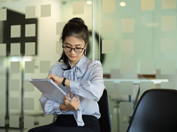 Speed to hire. A woman in an office checks her watch.