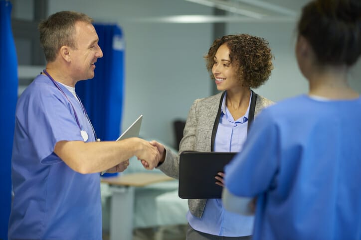 Improving workplace culture in skilled nursing facilities. A group of healthcare workers meet and shake hands.