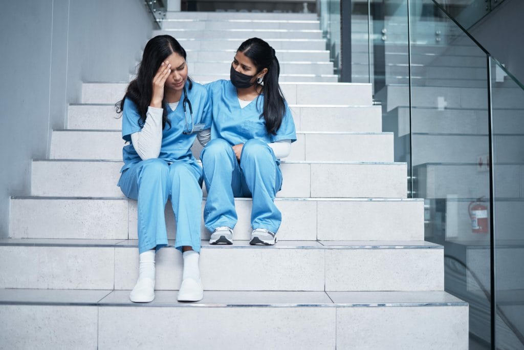 Two nurses comfort each other after a touch moment. Community and peer support can help stop nurse burnout.