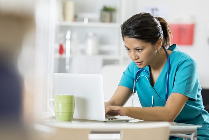 Effective job ads. A healthcare worker looks at a computer screen.