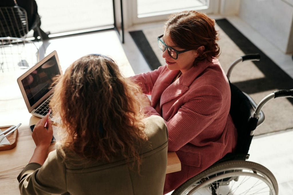 AI recruitment. Two women in an office look at a computer together.