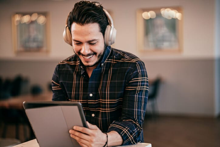 Indeed sponsorships. A man smiles while looking at something on a mobile tablet.
