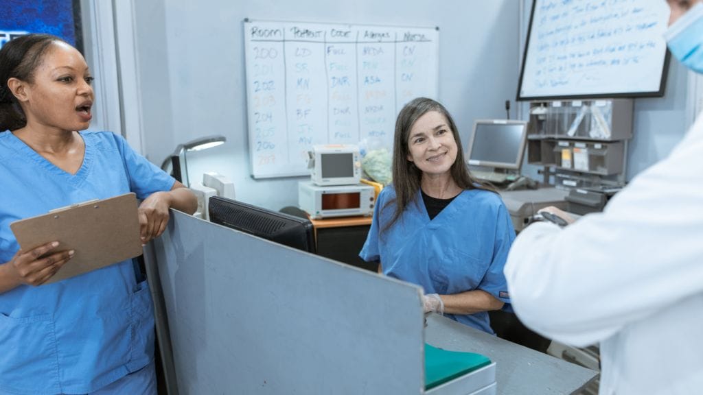 two nurses discuss compliance with a doctor after an effective training