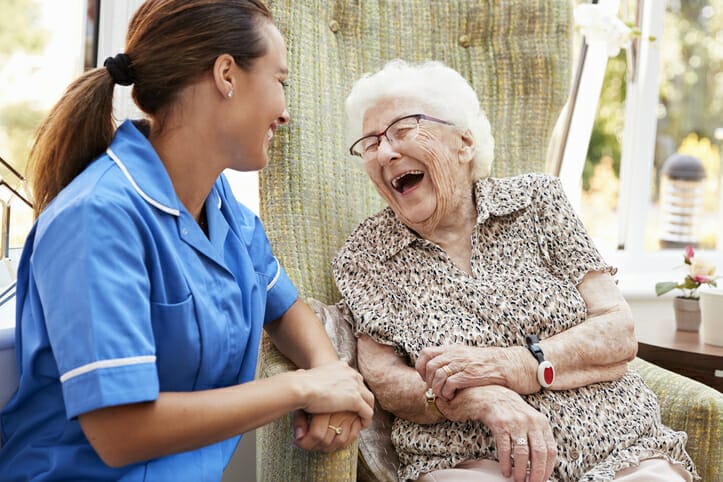 An older woman and a caregiver laugh together