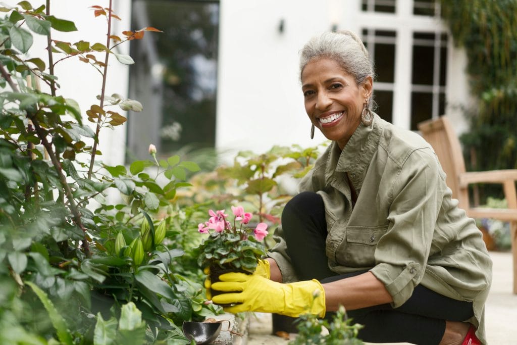 Happy retired senior woman gardening in back yard