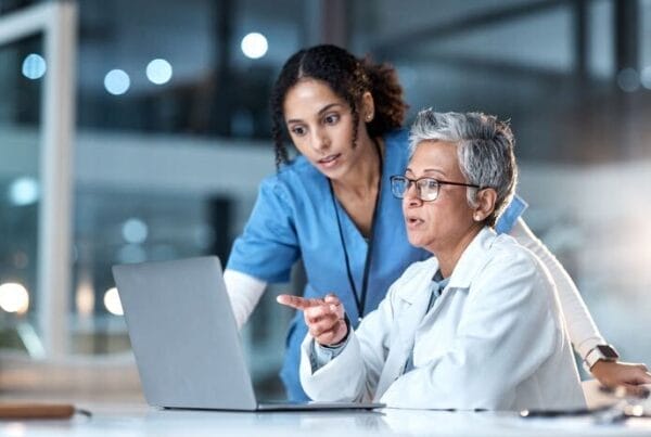 Two health care providers discussing and referring to a computer screen